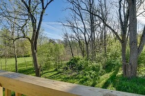 Une terrasse en bois donnant sur un espace verdoyant, agrĂ©mentĂ© dâarbres et dâarbustes.