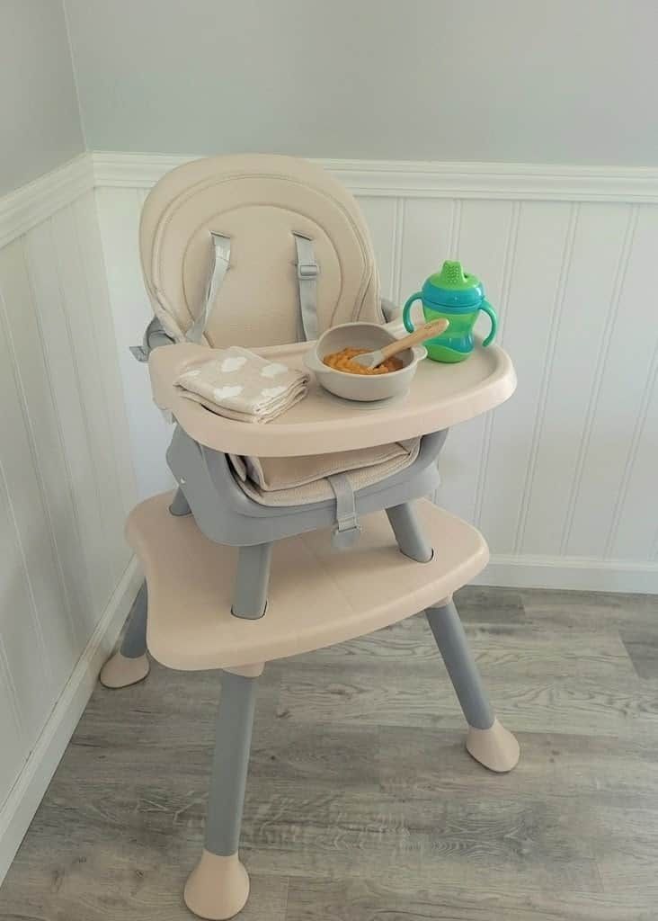 A high chair with a tray table and a green sippy cup.
