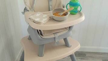 A high chair with a tray table and a green sippy cup.