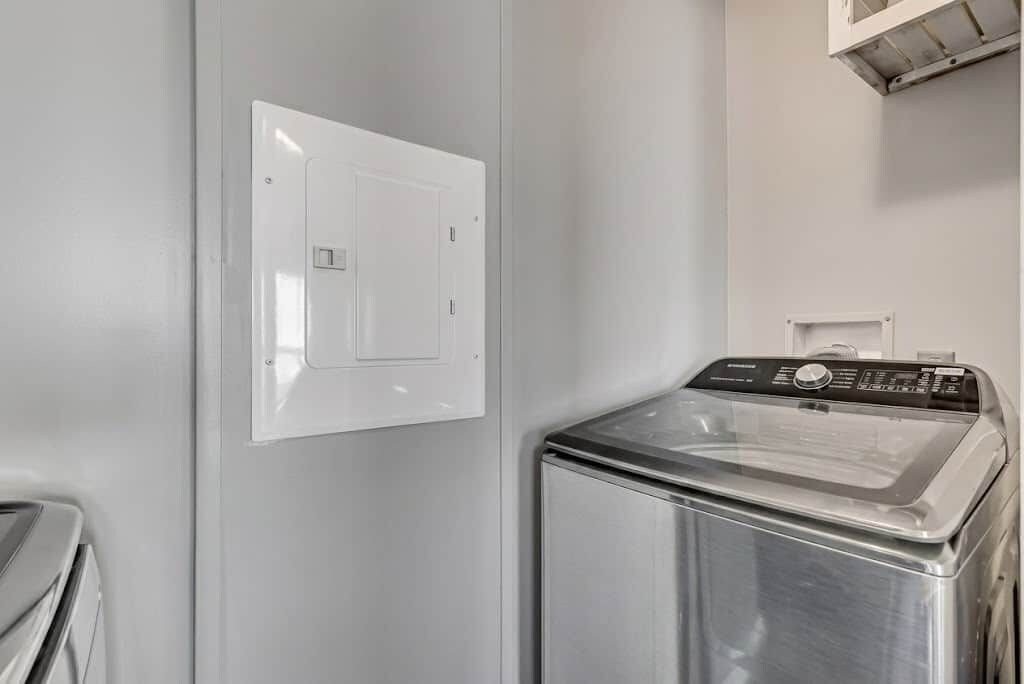 Uma lavanderia compacta com máquina de lavar e painel de controle na parede.