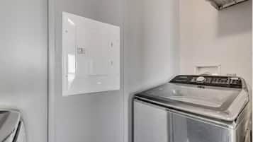 Uma lavanderia compacta com máquina de lavar e painel de controle na parede.