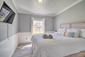 A bedroom with a bed, a television mounted on the wall, and a window with curtains. - Family-Friendly By Fishing, Hiking, and Wine Trail (Seneca Falls)