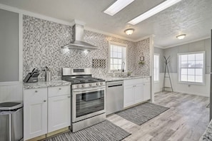 Une cuisine moderne avec des meubles blancs, une cuisinière en acier inoxydable et un dosseret décoré.