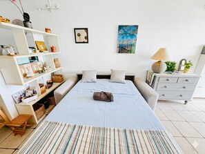 Une chambre à coucher comprenant un lit, des tables de chevet, une commode, une étagère avec divers objets et des œuvres d’art accrochées au mur.