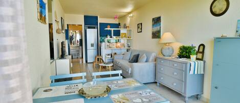 A dining area with a table set for four, a sofa, and a cabinet.