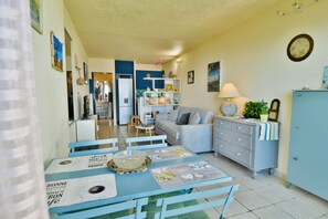 Uma sala de jantar com uma mesa posta para quatro pessoas, um sofá e um armário.