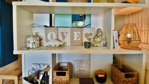En hylde med dekorative genstande, heriblandt et 'LOVE' skilt, en Buddha-figur og diverse kurve.