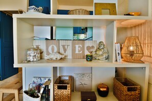 A shelf with decorative items including a 'LOVE' sign, a Buddha statue, and various baskets. - Rarissime Studio with sea view & 17 m swimming pool | Absolute peace and quiet | 10 min from the beach (Hyères)