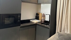 Una cocina moderna con electrodomésticos integrados, un comedor con sofá gris y una ventana con cortinas.