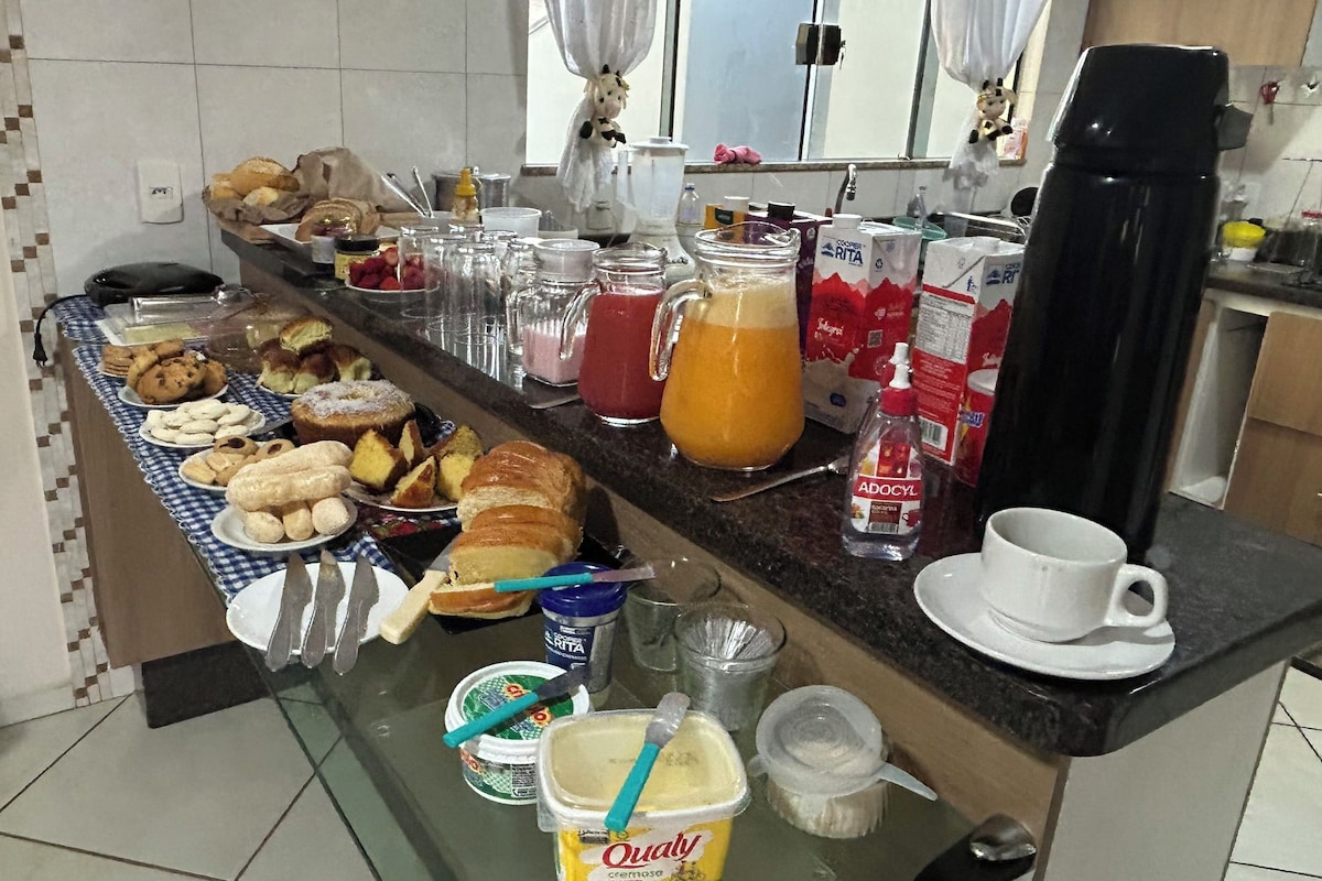 A breakfast buffet with various pastries, a coffee machine, and condiments.