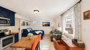 Ein kompakter Wohnbereich mit Küchenzeile, Essplatz, Sofa und kleinem Tisch.