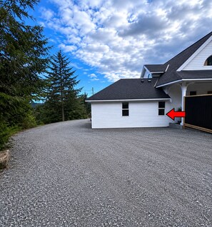 A house with a gravel driveway, a garage with a black gate, and a small window on the side.