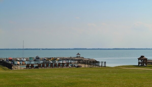 A coastal area with a fenced beach, a gazebo, and a pier with boats.