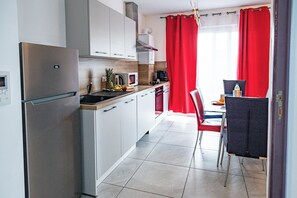 A modern kitchen with a refrigerator, microwave, and coffee maker. - Abracadabra Flat France Suisse near airport (Saint-Louis)