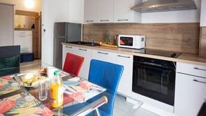 Moderni keittiö, jossa on mikroaaltouuni, uuni ja ruostumattomasta teräksestä valmistetut kodinkoneet.