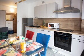 A modern kitchen with a microwave, oven, and stainless steel appliances. - Abracadabra Flat France Suisse near airport (Saint-Louis)