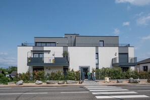 A modern two-story building with balconies, a crosswalk, and a clear sky. - Abracadabra Flat France Suisse near airport (Saint-Louis)