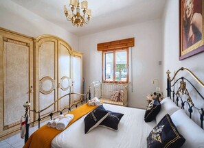 A bedroom with a bed, a wardrobe, a radiator, a window, and a chandelier. - Eden Villa Privata Sul Mare (Porto Cesareo)