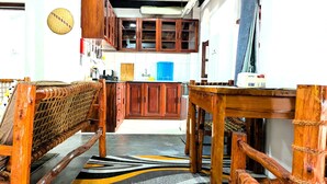 A kitchen with wooden cabinets, a woven bench, and a patterned rug. - The Hub Train House Amazing Gents code (Zanzibar)