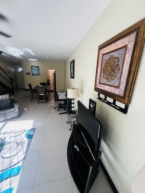A living room with a sofa, a TV, a coffee table, and a dining area with chairs and a table.
