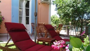 A sun lounger with a red cushion, a wooden chair, and a small table. - Aiolos Rooms (Tsoukalades)