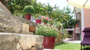 A stone staircase leading to a garden with potted plants and a purple chair. - Aiolos Rooms (Tsoukalades)