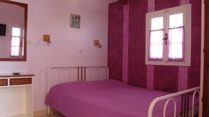 A bedroom with a single bed, a desk, a mirror, and a window with curtains. - Aiolos Rooms (Tsoukalades)