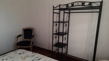 Un dormitorio con cama, una silla y un armario metálico con estantes.