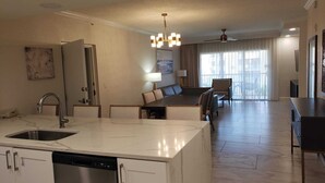 A modern hotel room with a kitchen, dining area, and a balcony with curtains. - Luxurious resort stay with amazing all-inclusive amenities near Orlando Florida! (Kissimmee)