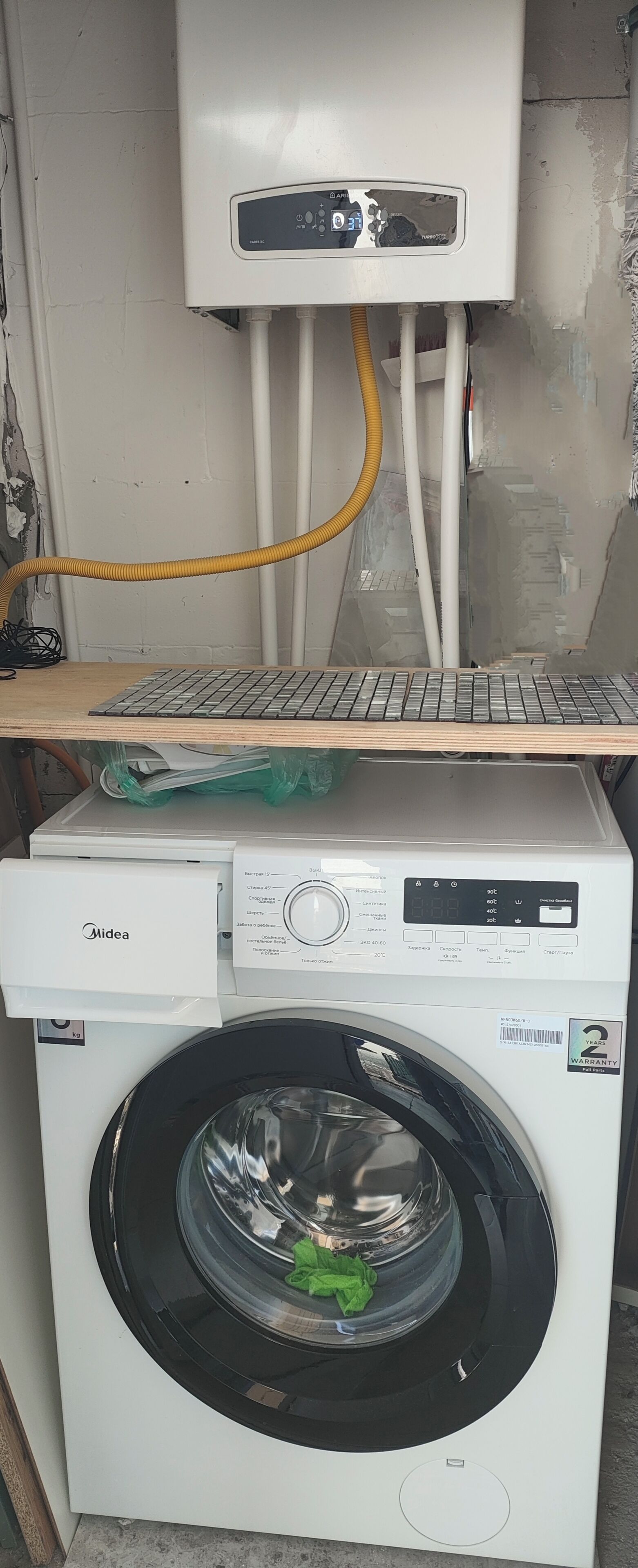 Une machine à laver et un chauffe-eau sont empilés l’un sur l’autre, et un clavier est posé sur le dessus.