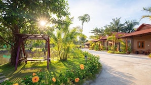 A pathway leading to a row of houses with a pergola and flowers in the foreground. - Serene Resort in Bai Vong Phu Quoc (Phu Quoc)