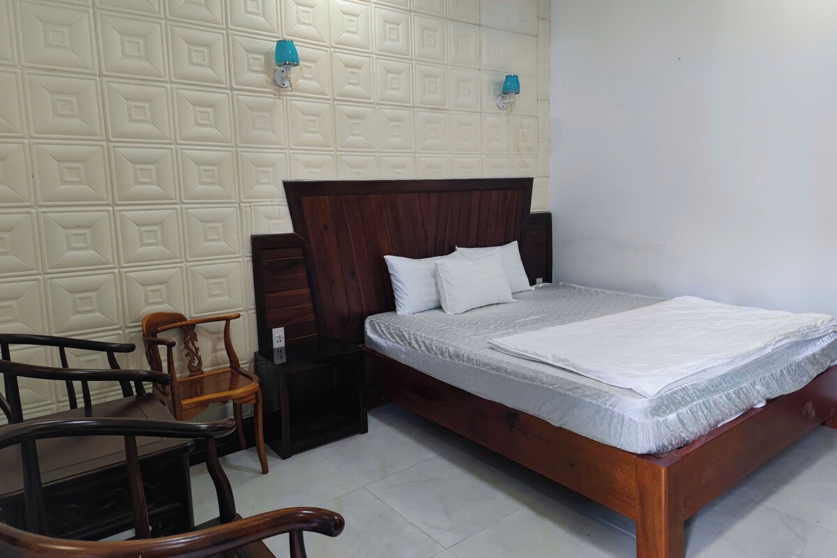 Un dormitorio con una cama de madera, dos lámparas de pared, una mesita de noche y una silla.