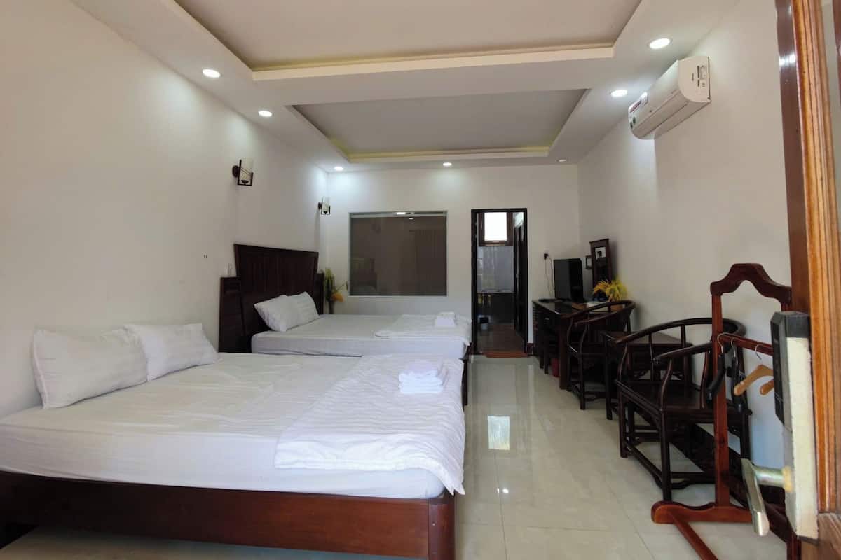 Habitación de hotel con dos camas, un escritorio, una silla y un televisor.