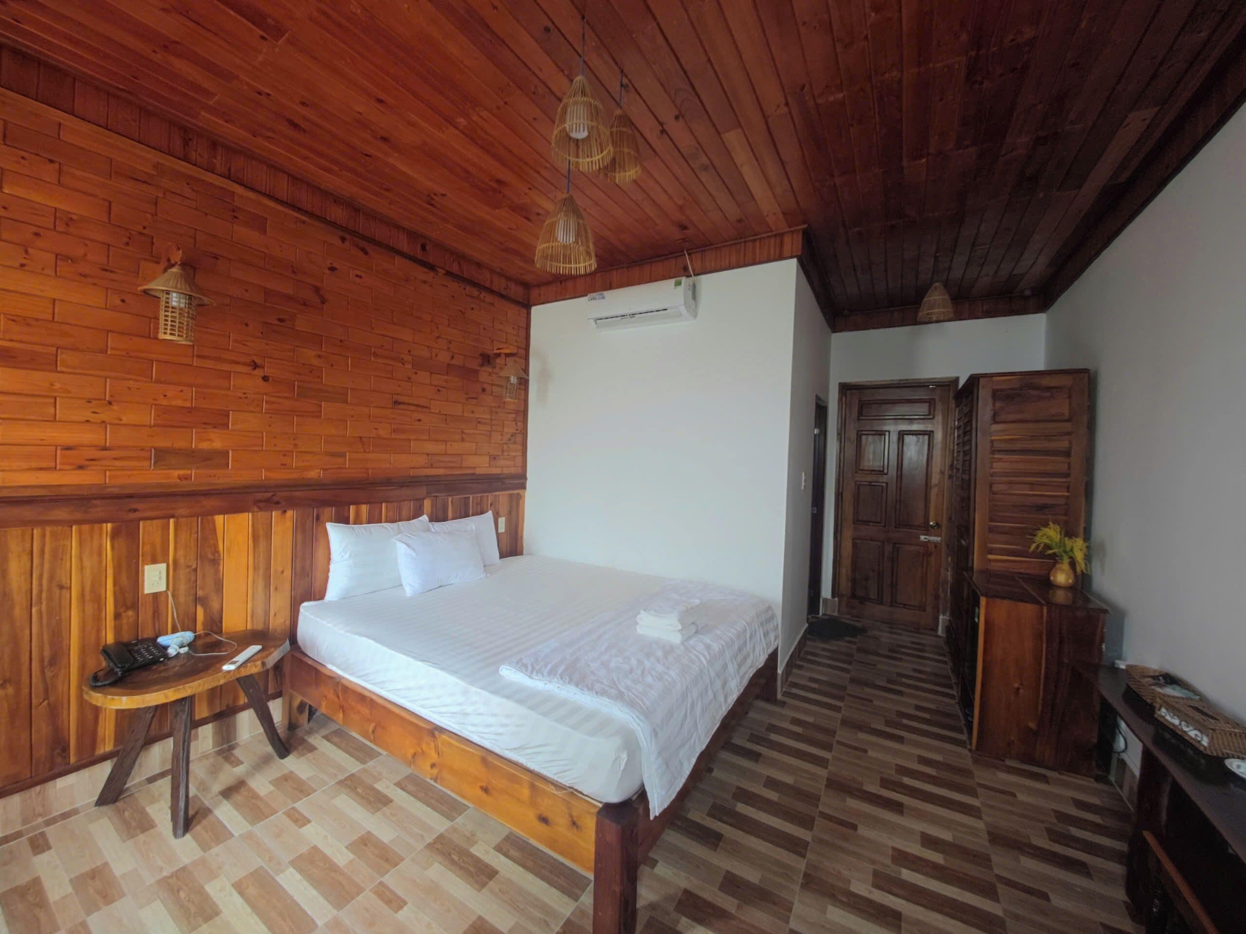 Un dormitorio con paneles de madera, una cama, una mesita de noche y una pequeña mesa con una lámpara.
