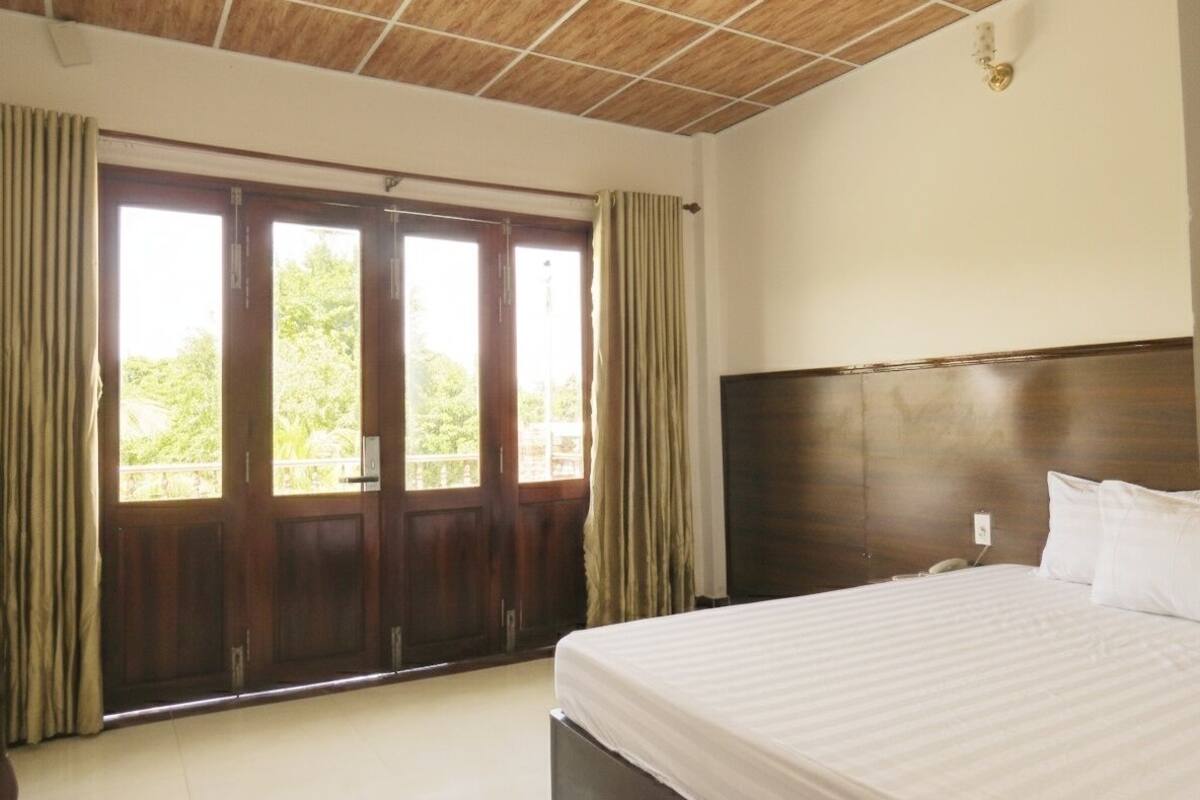 Un dormitorio con una cama grande, techo de madera y vistas a través de un ventanal corredero.