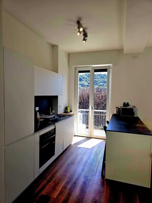 Una cucina moderna con forno a incasso, forno a microonde e macchina del caffè sul piano di lavoro.