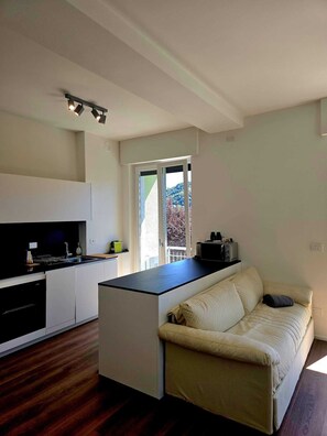 Una cucina moderna con isola centrale, forno a incasso e zona pranzo con divano.