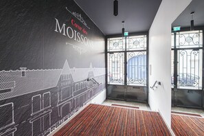 Un interior moderno con un mural de un paisaje urbano, una escalera y una puerta con reja de metal.