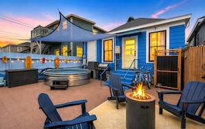 Ein Garten mit Whirlpool, Sitzgelegenheit und Feuerstelle.