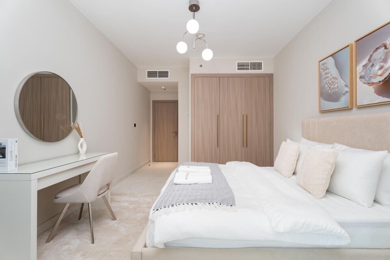 A bedroom with a bed, a desk, a chair, a mirror, and a wardrobe.