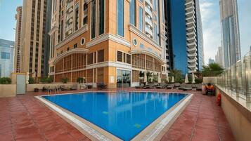 A rooftop pool with a clear blue pool, surrounded by high-rise buildings, and outdoor seating areas.