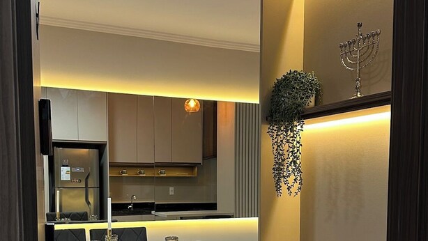 A modern kitchen with built-in appliances, a dining area with a table and chairs, and a decorative shelf with plants. - 3-bedroom condo with beautiful views, pool, gym & gardens at Salto del Monday (Franco)