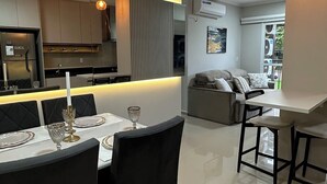 A modern kitchen with built-in appliances, a dining area with a table set for two, and a living area with a sofa and a coffee table. - 3-bedroom condo with beautiful views, pool, gym & gardens at Salto del Monday (Franco)