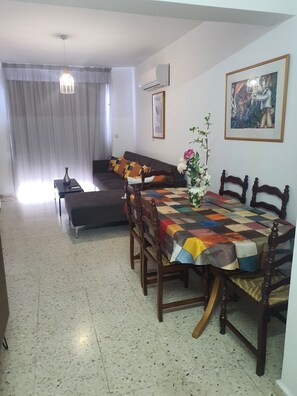 Un coin repas avec une nappe à carreaux, des chaises en bois, un canapé et un vase rempli de fleurs.