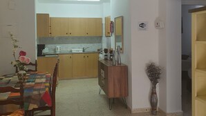 A dining area with a table, chairs, and a vase of flowers. - Latchi Harbour 2-bedroom Penthouse (Poli Chrysochous)
