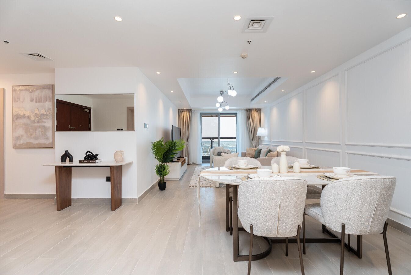 A modern hotel room with a dining area, a living space, and a view of the city.