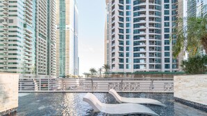 A modern high-rise building with a swimming pool and decorative swan sculptures. - Gala Guests - Princess Tower Suites (Dubai)