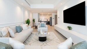 A modern living room with a sofa, coffee table, and a flat-screen TV mounted on the wall. - Gala Guests - Princess Tower Suites (Dubai)