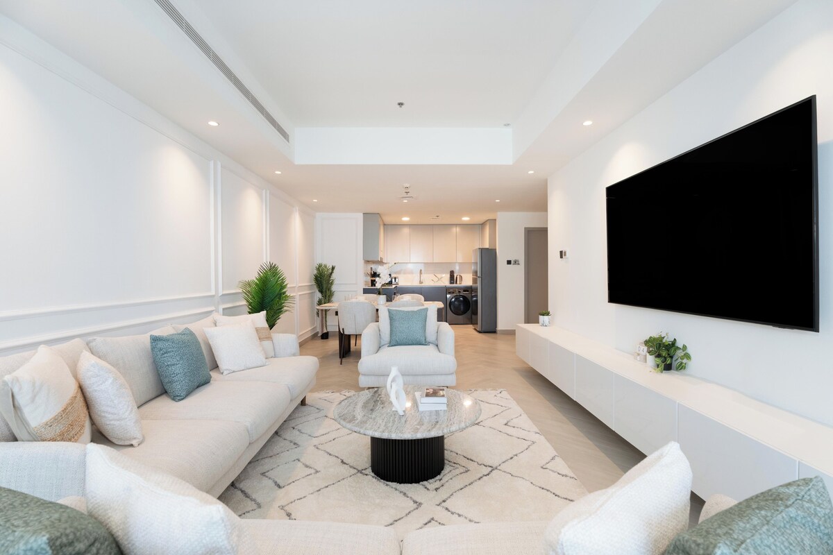 Ein modernes Wohnzimmer mit einer Couch, einem Couchtisch und einem an der Wand befestigten Flachbildfernseher.