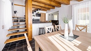 A modern kitchen with wooden beams, a dining area with a wooden table, and a staircase.